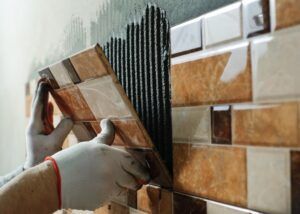 Laying Ceramic Tiles. Tiler placing ceramic wall tile in position over adhesive